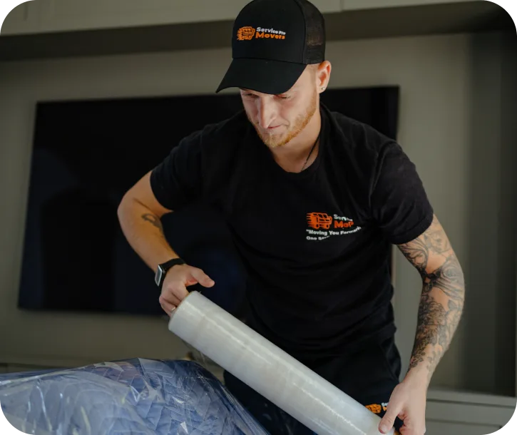 Service Pro Movers worker wrapping furniture for piano movers service in home.