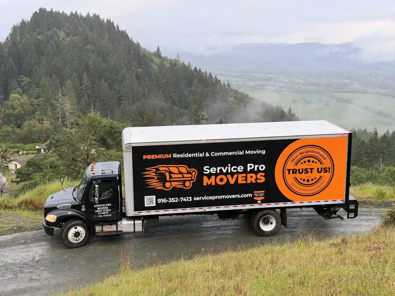 Team of interstate movers standing next to branded truck ready for long-distance move