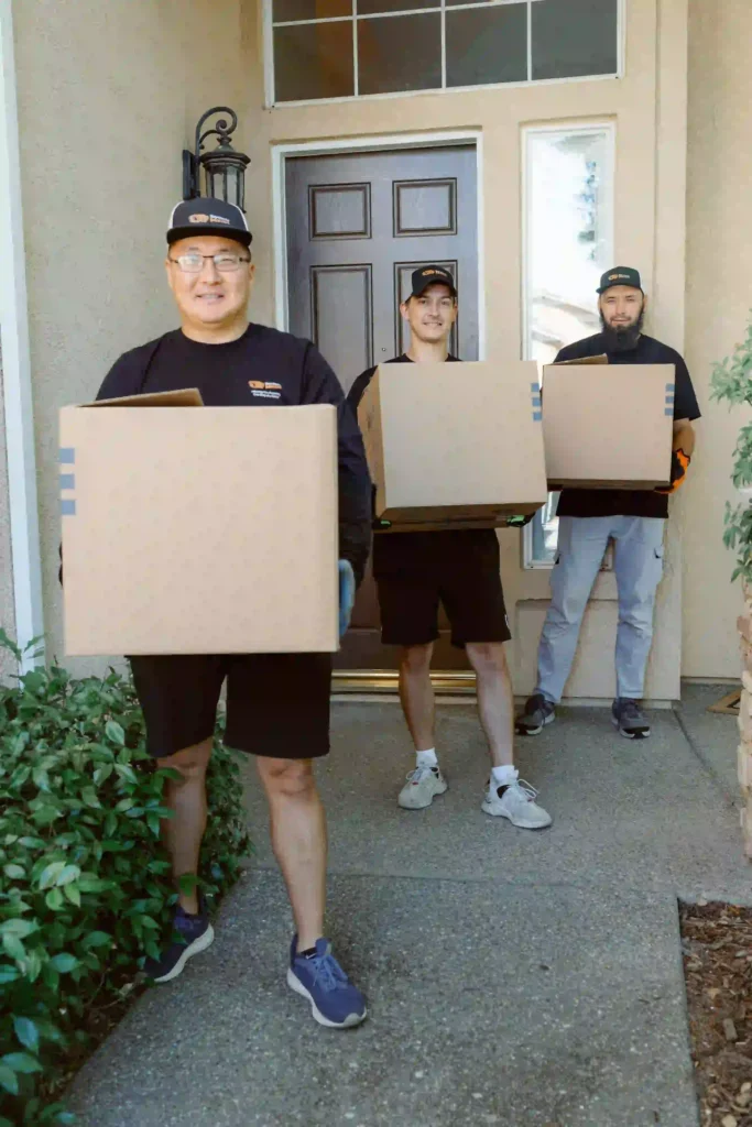 Professional local movers from Service Pro Movers holding cardboard boxes while helping a student move out of a Sacramento apartment