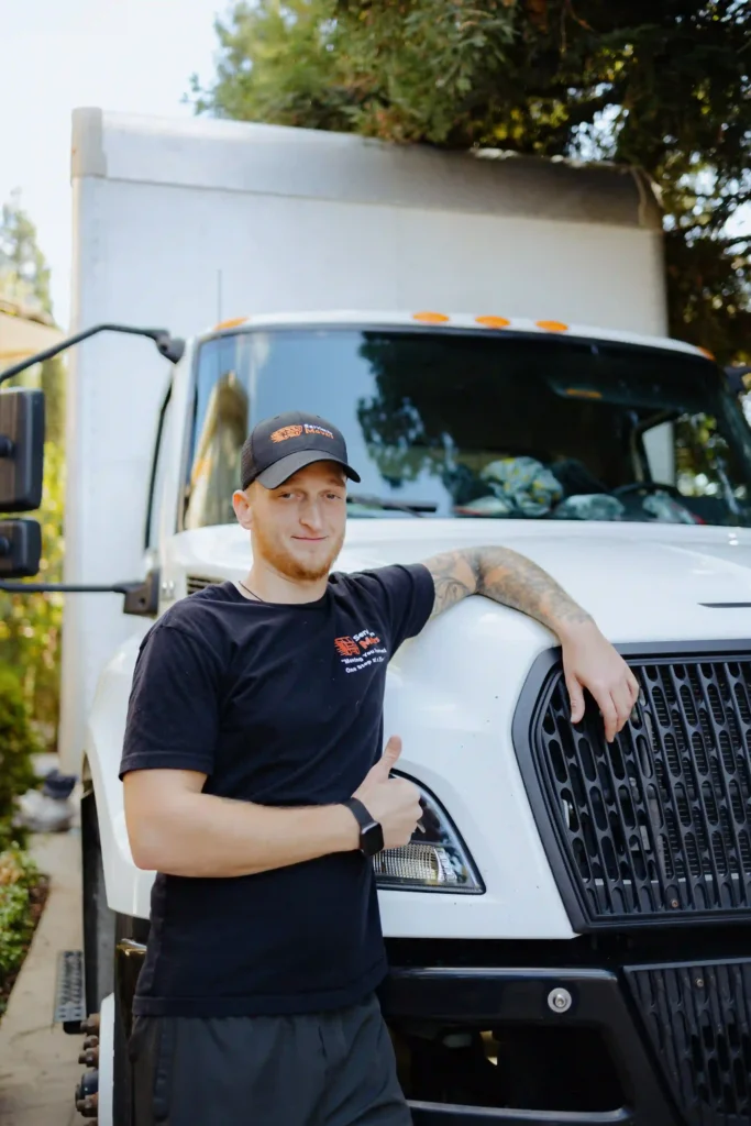 A friendly Service Pro Movers team member in a branded uniform leaning against a professional moving truck in Sacramento, California